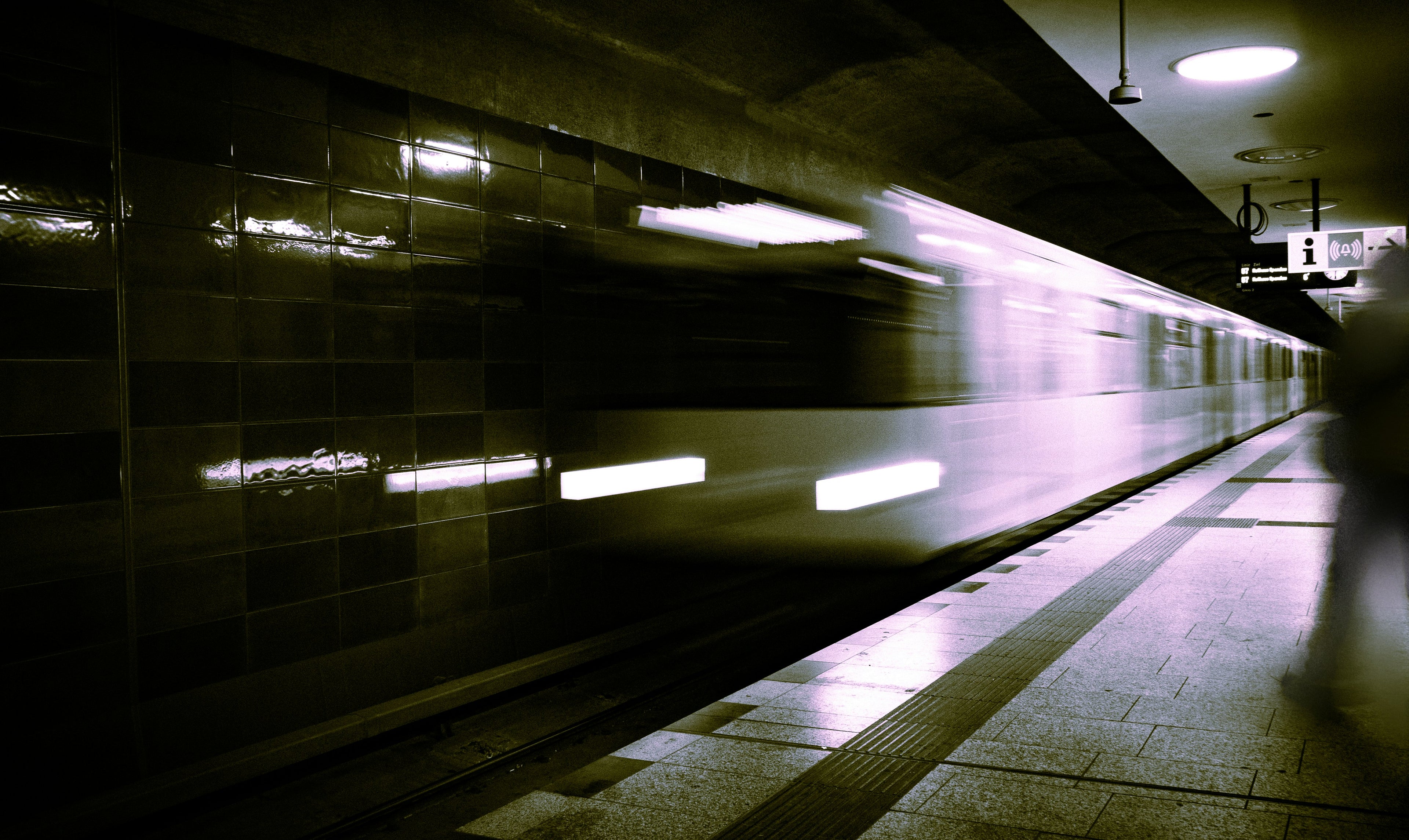 A blurred image of a subway train passing through a station, emphasizing motion and urban life.